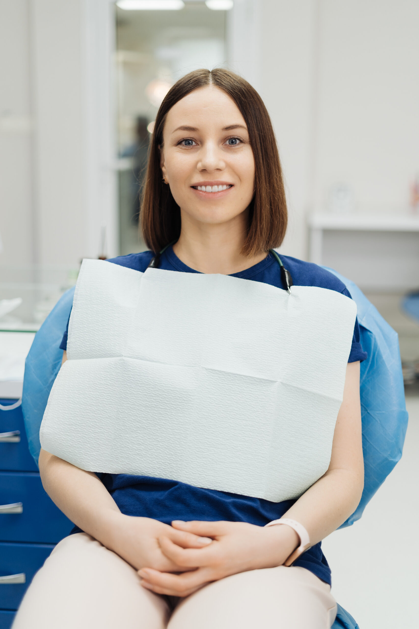 Smiling Caucasian young woman patient at dentist health check sitting in stomatology chair looking at camera